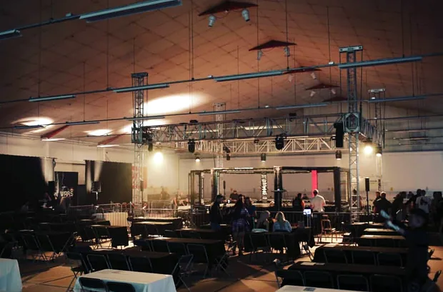 The arena dressed for a fight night: lighting truss rigged over the octagon, with tables and seating set out around it