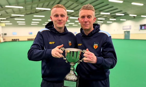 The men's pairs winners with their cup on the green
